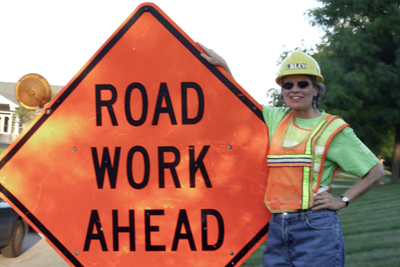 Teresa in front of Road Work Ahead traffic sign.
